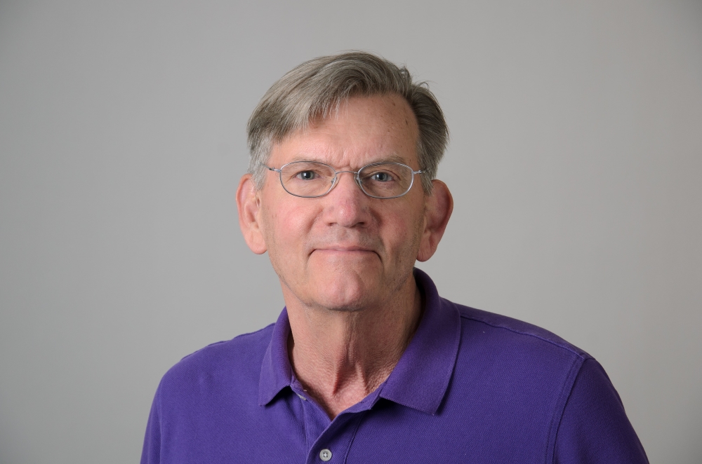 Portrait of Ken Foote with grey background and glasses.