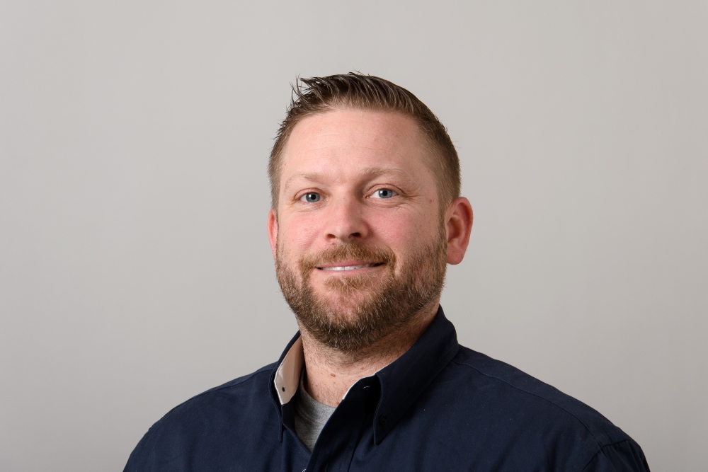 Portrait of Gary Mackiewicz wearing a blue collared shirt.